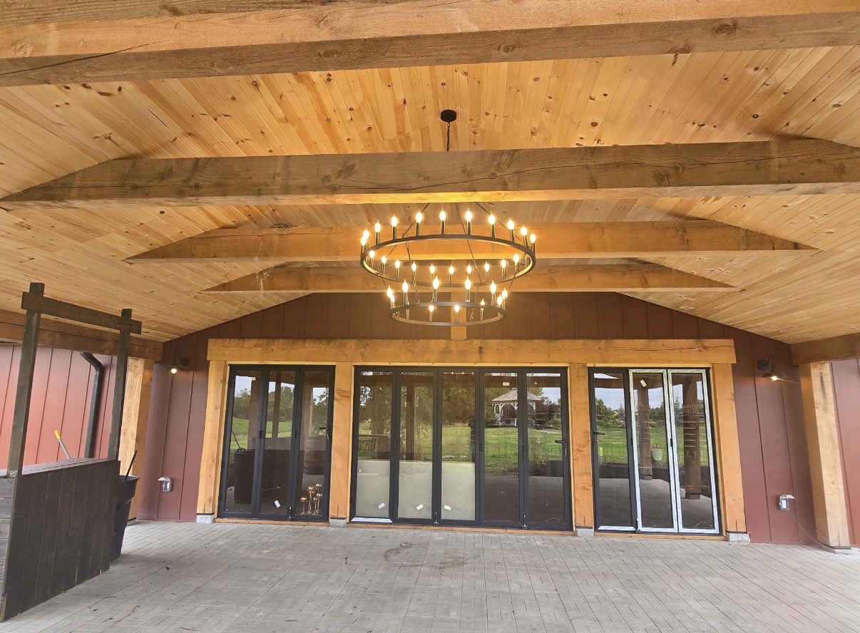 Covered timber-frame porch with a chandelier overlooking the estate grounds