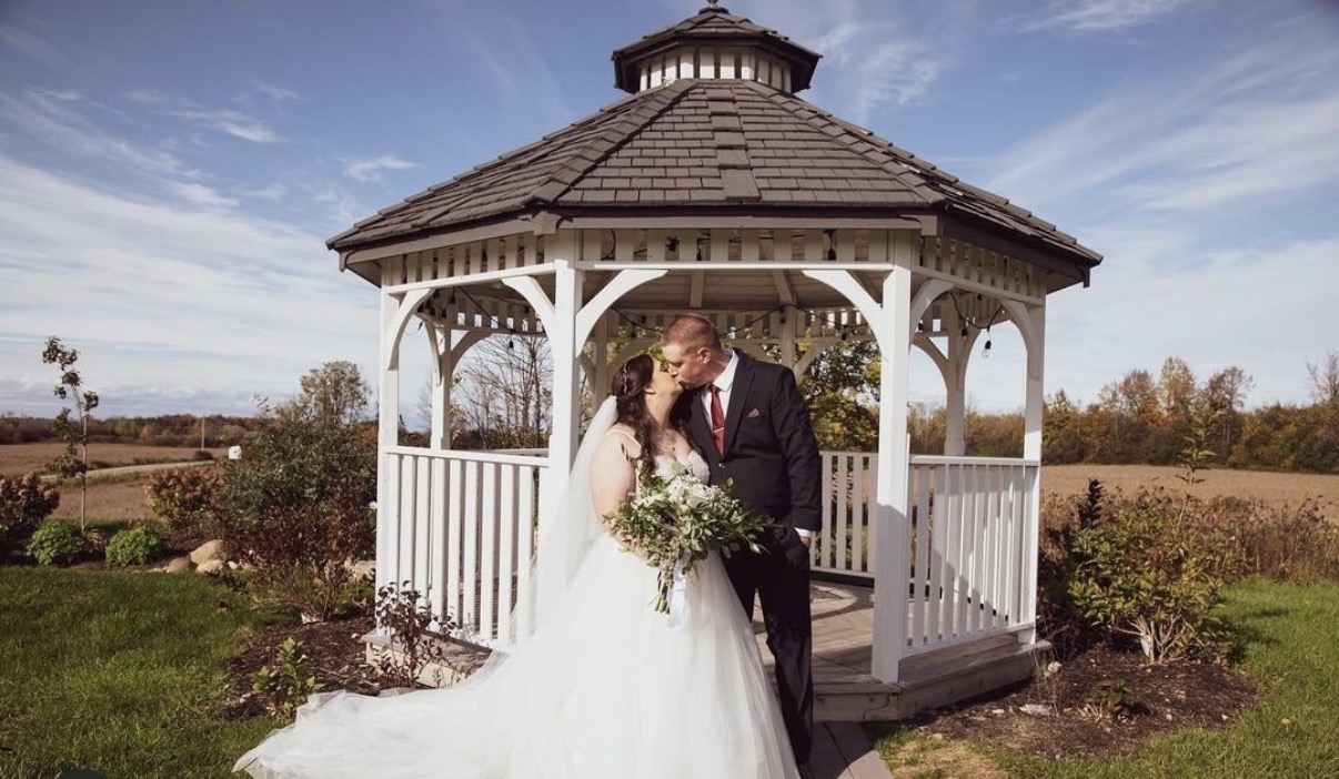 Bride and groom sharing a kiss in the white garden gazebo at SV Country Estate