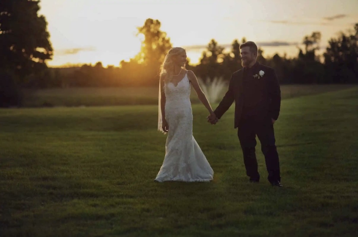Bride and groom holding hands on the estate lawn at sunset