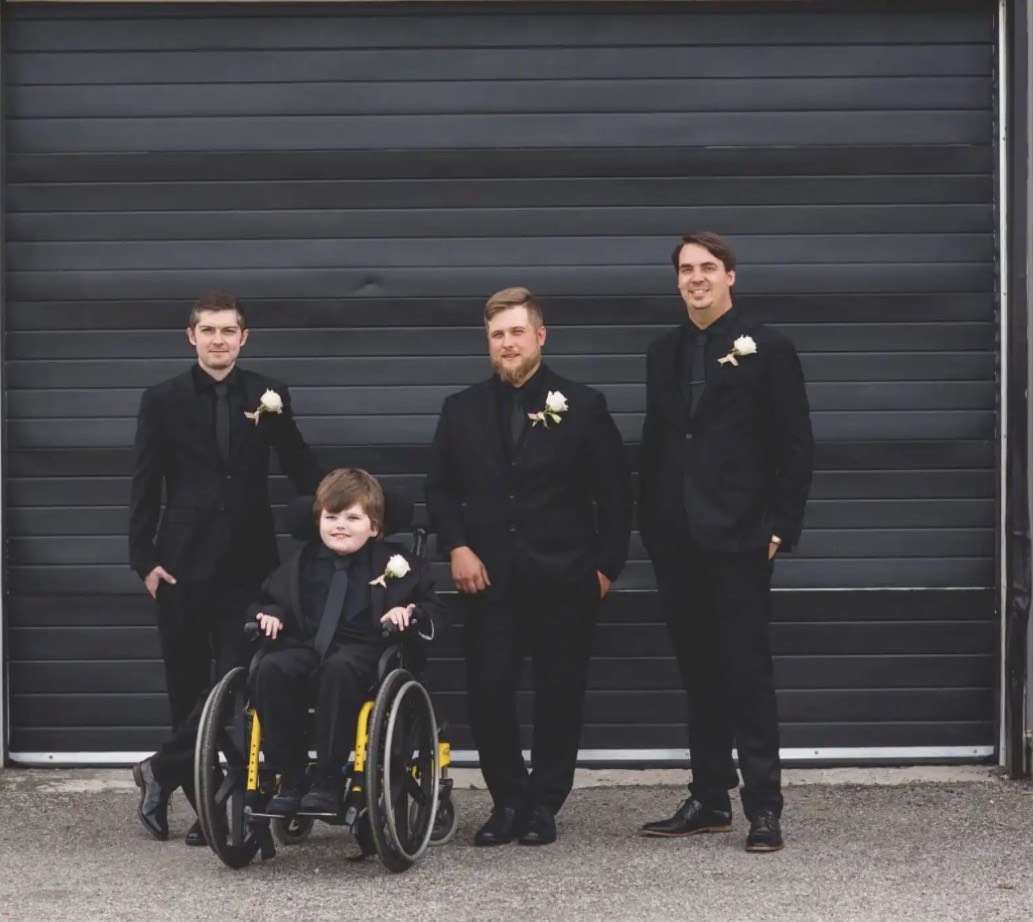 Groomsmen and ring bearer in black suits with white boutonnieres at the estate